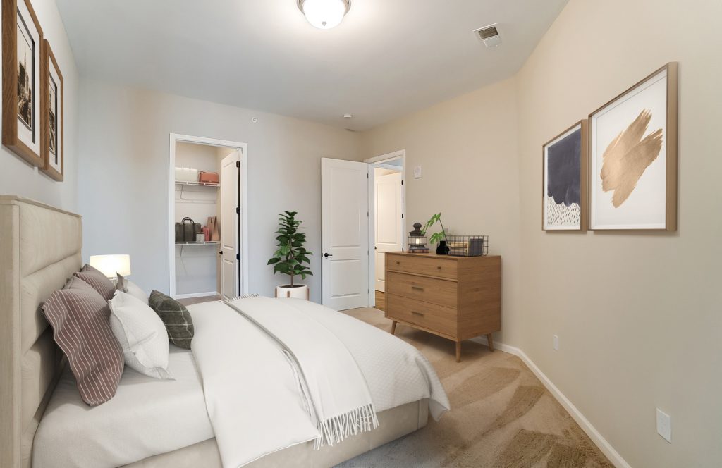 Essex Unit D bedroom with bed in forefront and peak view into walk in closet